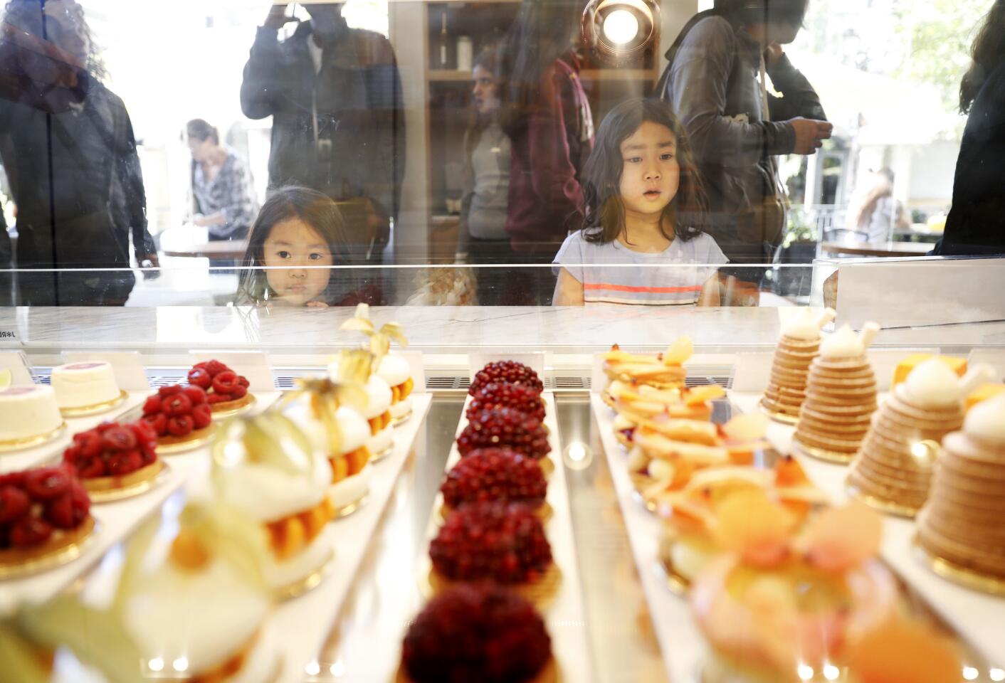 Three-year-old Lydia Sebata, left, and her sister Candice, 5, right, peer into the glass case at Dominique Ansel Bakery at the Grove in Los Angeles.
