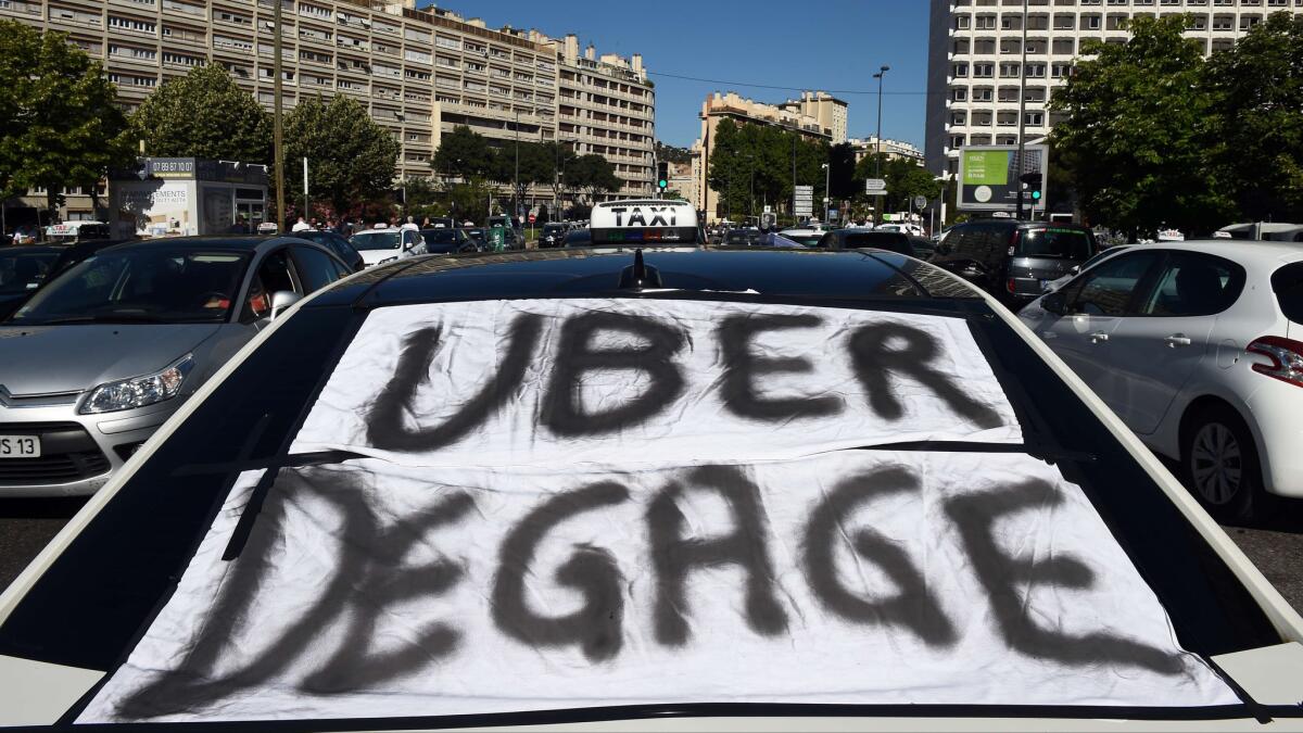A banner across a taxi windshield in Marseille, France, last year displays the message, "Uber, get out."