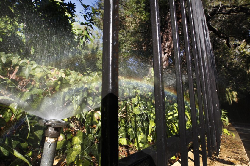 A rainbow forms in the spray as sprinklers water a residence in Beverly Hills. Statewide, Californians cut their urban water use by almost 25% between June and February, regulators said Monday.