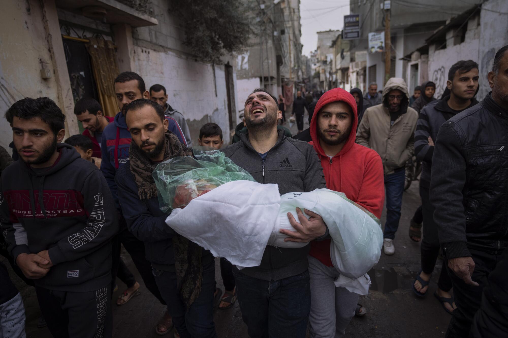 Gaza man carrying wrapped body of daughter who was killed in Israeli bombardment
