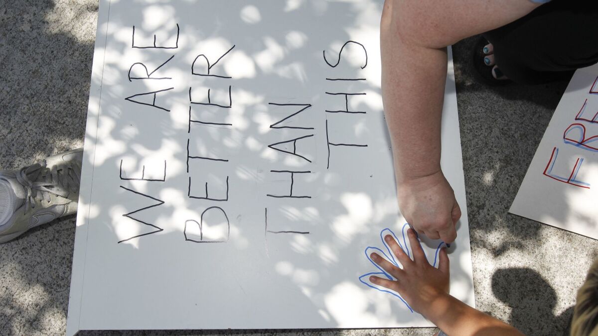 Robin Rizzo, from Lake Arrowhead, traces around the hand of her son Joseph Sotelo, 8, as they make a sign to protest in front of Casa San Diego, an El Cajon facility for boys, ages 6-17, who either arrived at the U.S. border unaccompanied or were separated from their parents.