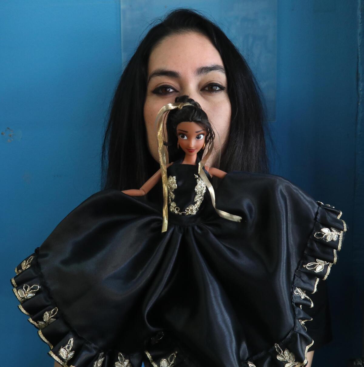 Latina comic book creator Kayden Phoenix stands behind a doll based on the main character of her graphic novel