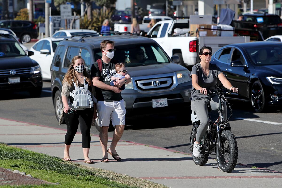 A couple and their child walk along South Coast Highway in Laguna Beach on Saturday.