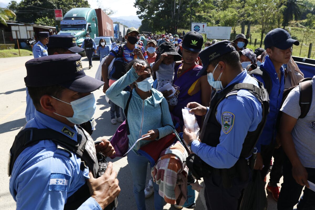Honduran police check documents of migrants who are part of a caravan hoping to reach the United States, in Corinto, Honduras, Saturday, Jan. 15, 2022. (AP Photo/Delmer Martinez)
