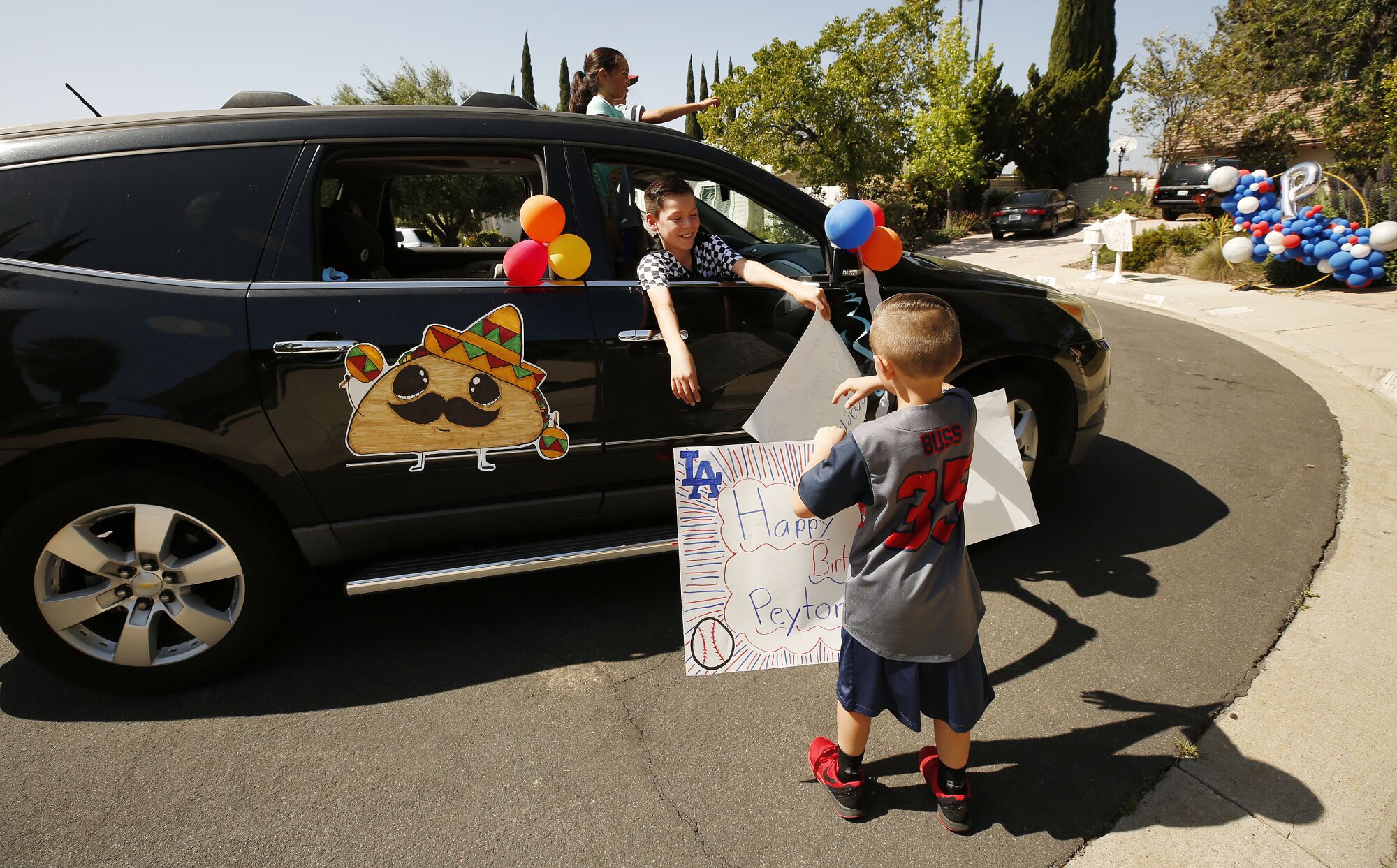 Mateo Ibarra hands off a sign to Peyton from a passing SUV.
