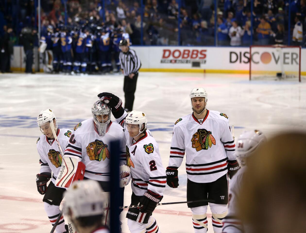 Blackhawks goalie Corey Crawford is consoled by Duncan Keith as the Blues celebrate their victory in triple overtime.