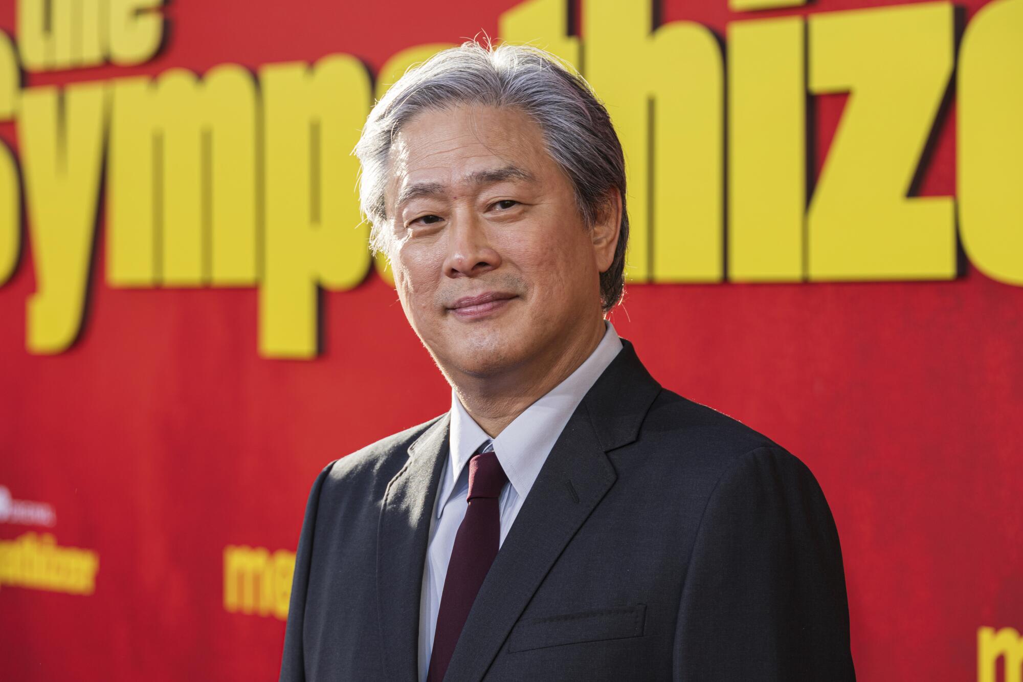 Park Chan-wook stand in front of a red backdrop with "The Sympathizer" logo on it.