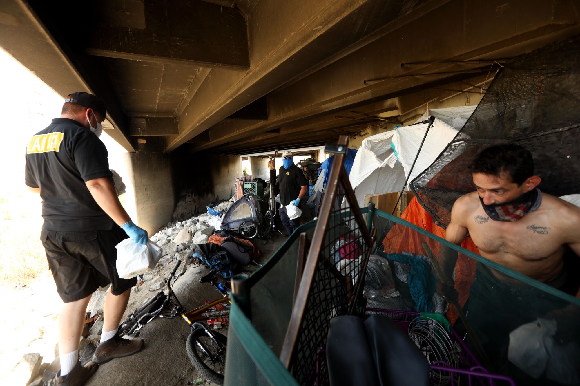LASHA outreach workers bring food for Greg Luckhart and others under the 605 Freeway in Arcadia.