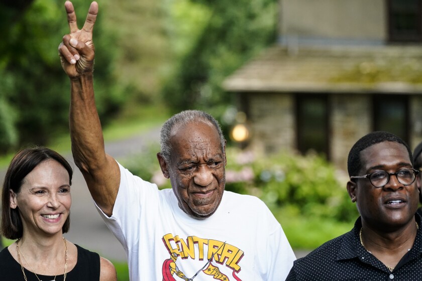 Bill Cosby, center, gives a victory sign