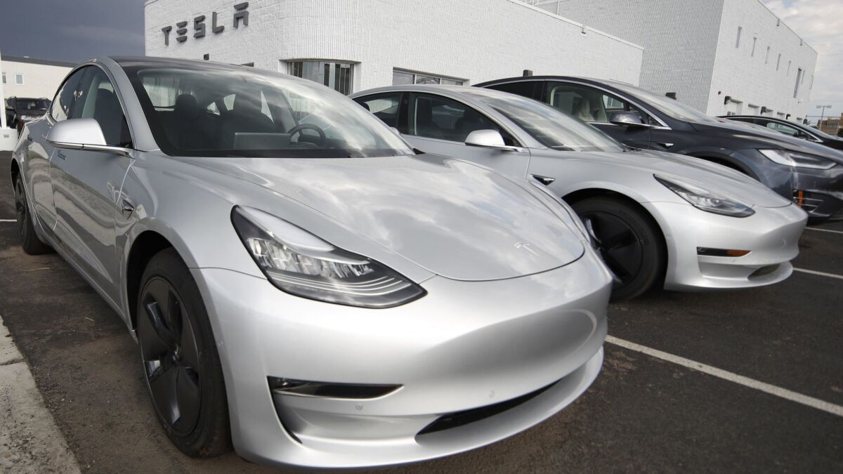 Model 3 sedans sit on display outside a Tesla showroom in Littleton, Colo. Tesla was trying to push as many electric cars out the door as possible before midnight Sunday, when the third quarter ended.