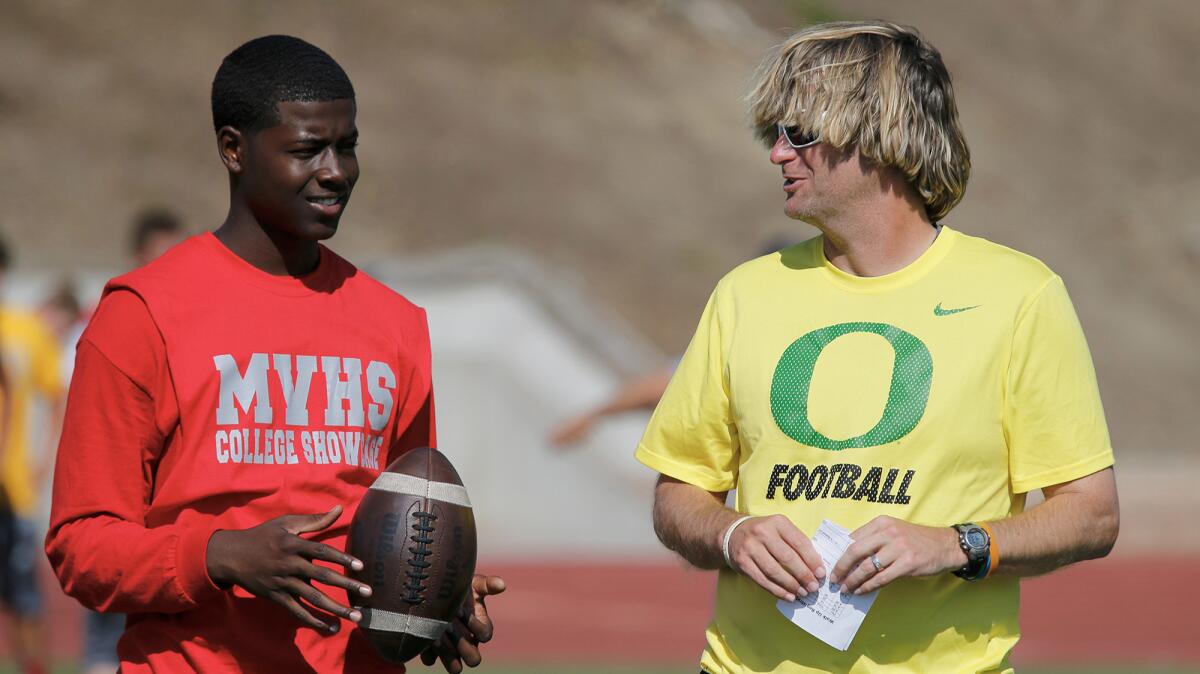 David Yost, Oregon's quarterbacks coach, talks to Upland High quarterback David Baldwin, left, during a satellite camp at Mission Viejo High School.
