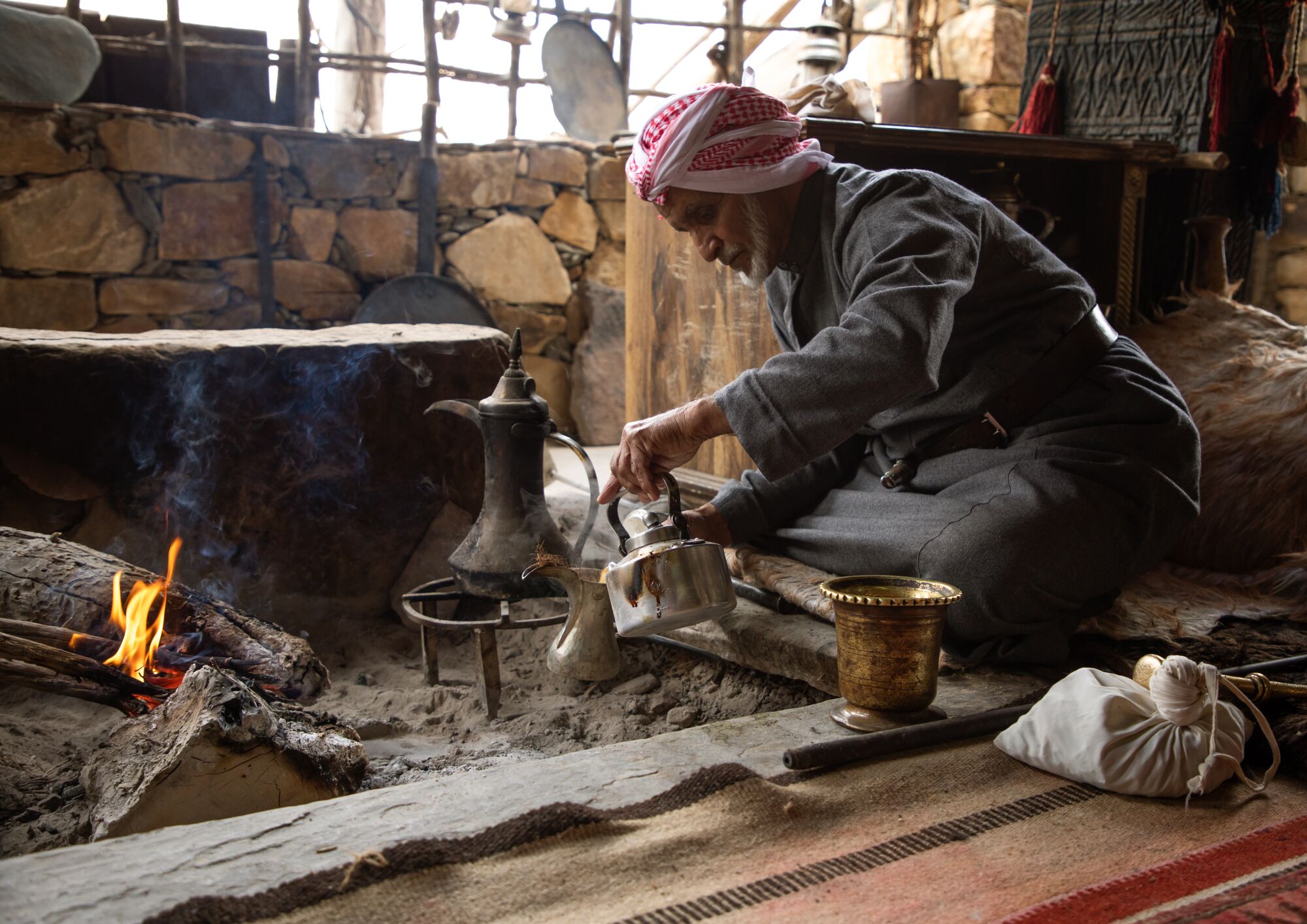   Suudi bir adam açık ateşin yanında kahve hazırlıyor.