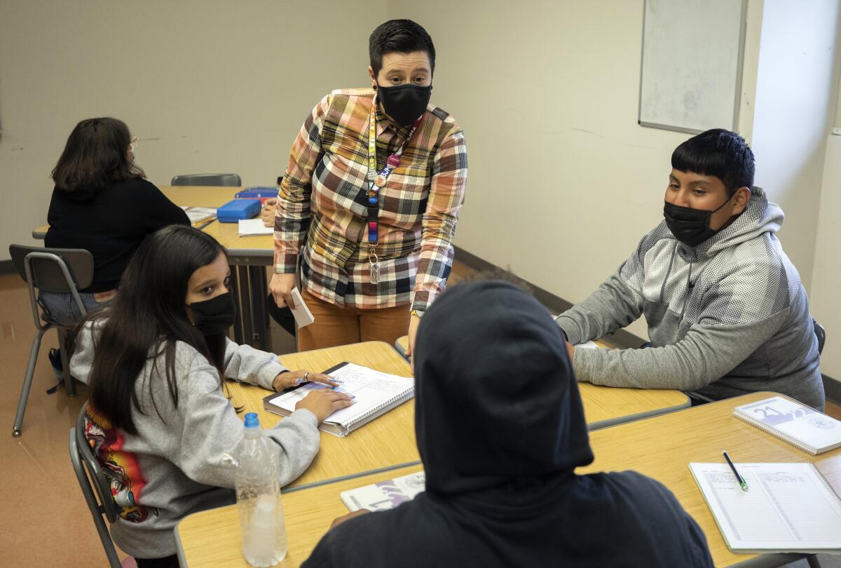 A teacher talks to students at their desks