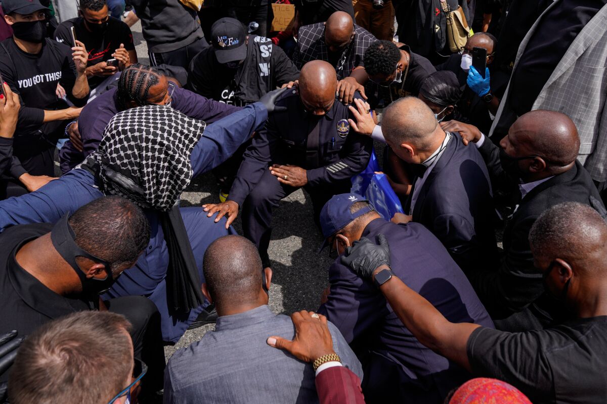 LAPD Commander Gerald Woodyard takes a knee with protesters and clergy members