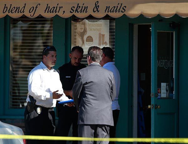 Police officers and detectives gather at the door to Salon Meritage in Seal Beach, where a gunman killed six people. Of three others who were wounded, two have died.