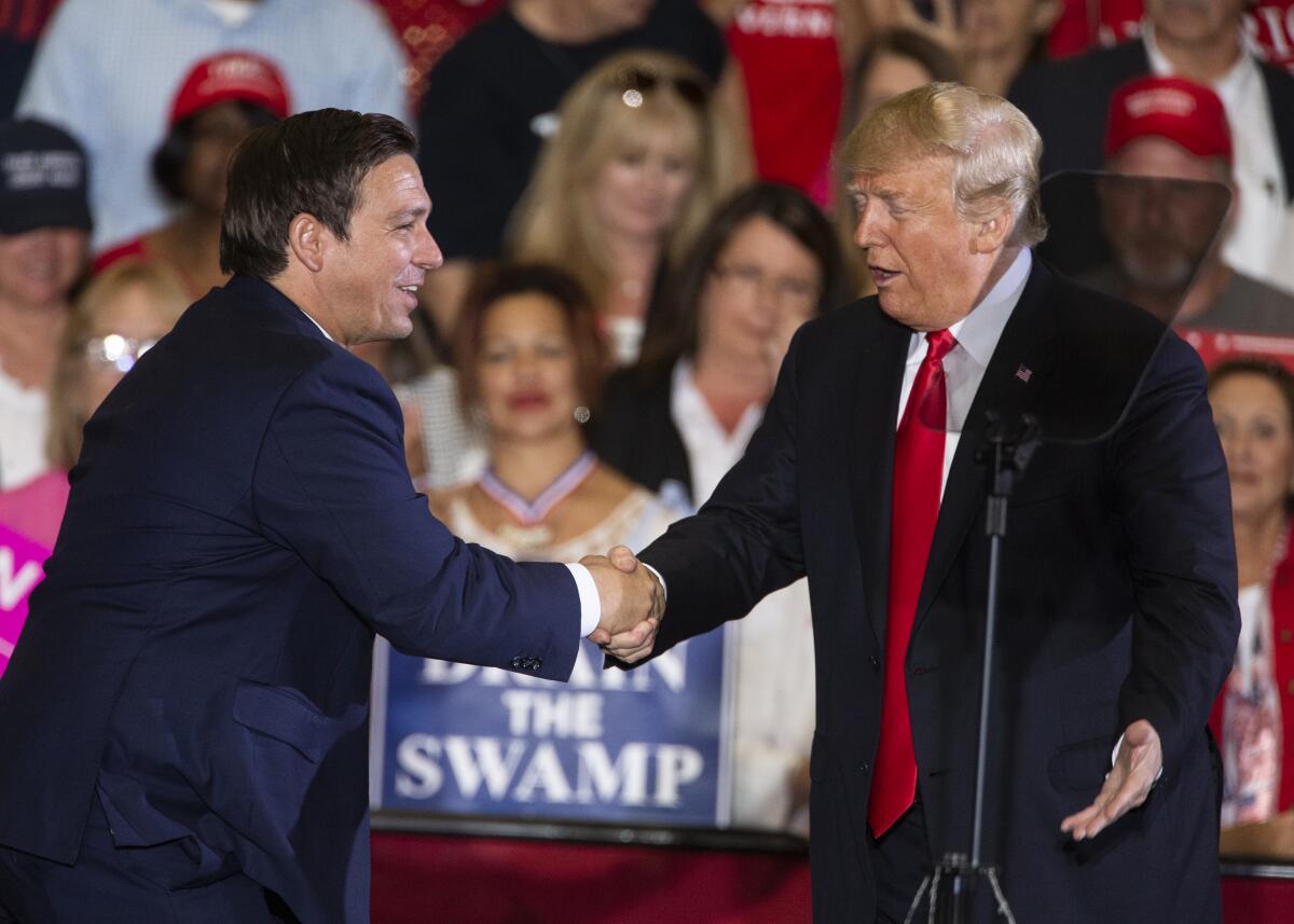 Then-President Trump shakes hands with Ron DeSantis.