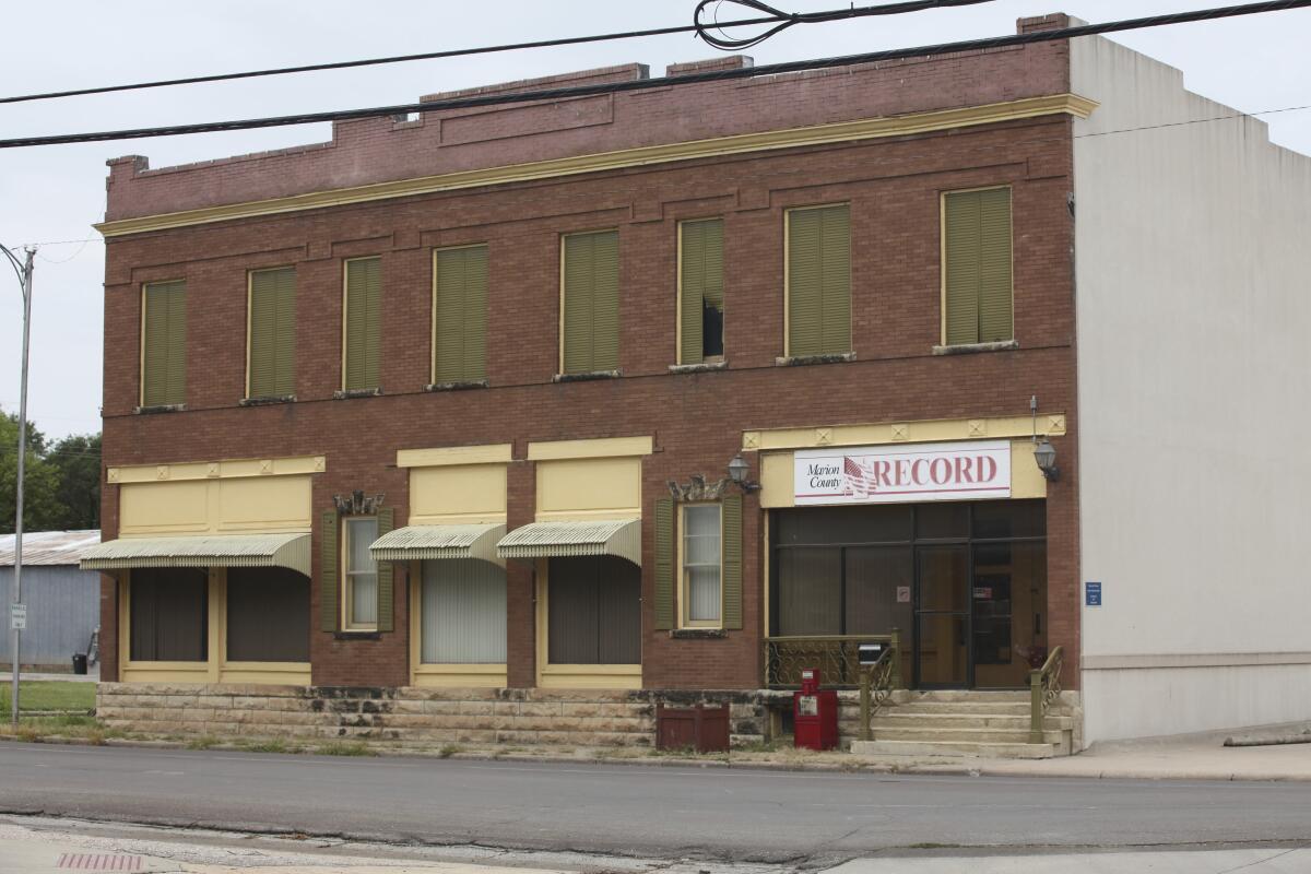 An older brick building with yellow trim and awnings and a sign reading "Marion County Record"