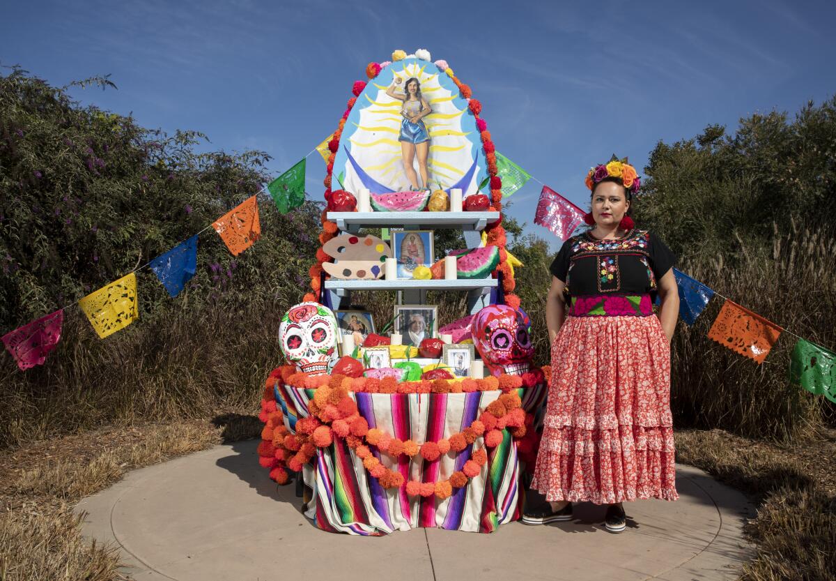 Artist Katie Ruiz stands next to brightly colored altar at botanic garden 