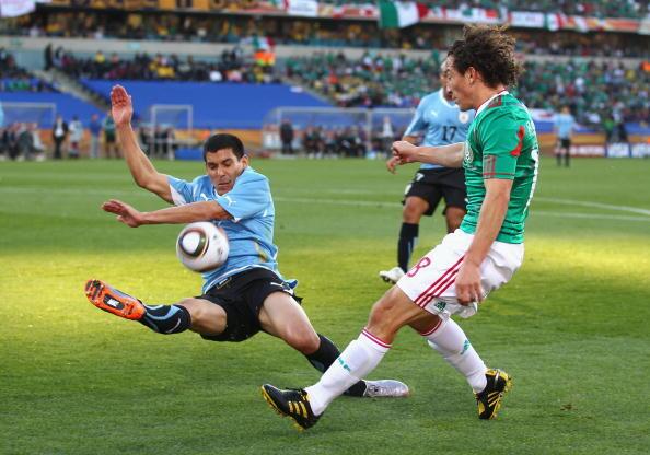 Maximiliano Pereira of Uruguay attempts to block the cross by Andres Guardado of Mexico during the 2010 FIFA World Cup South Africa Group A match between Mexico and Uruguay at the Royal Bafokeng Stadium on June 22, 2010 in Rustenburg, South Africa.