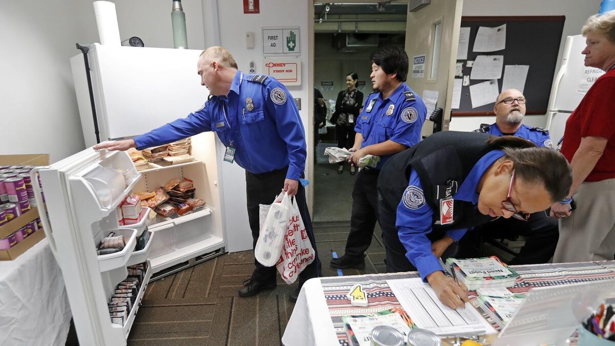 TSA workers look through a refrigerator stocked with meat at a temporary food pantry at John Wayne Airport set up by Second Harvest Food Bank of Orange County.