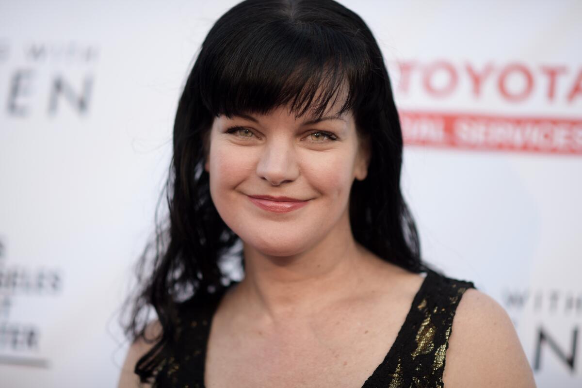 A woman with dark hair and bangs smiles.