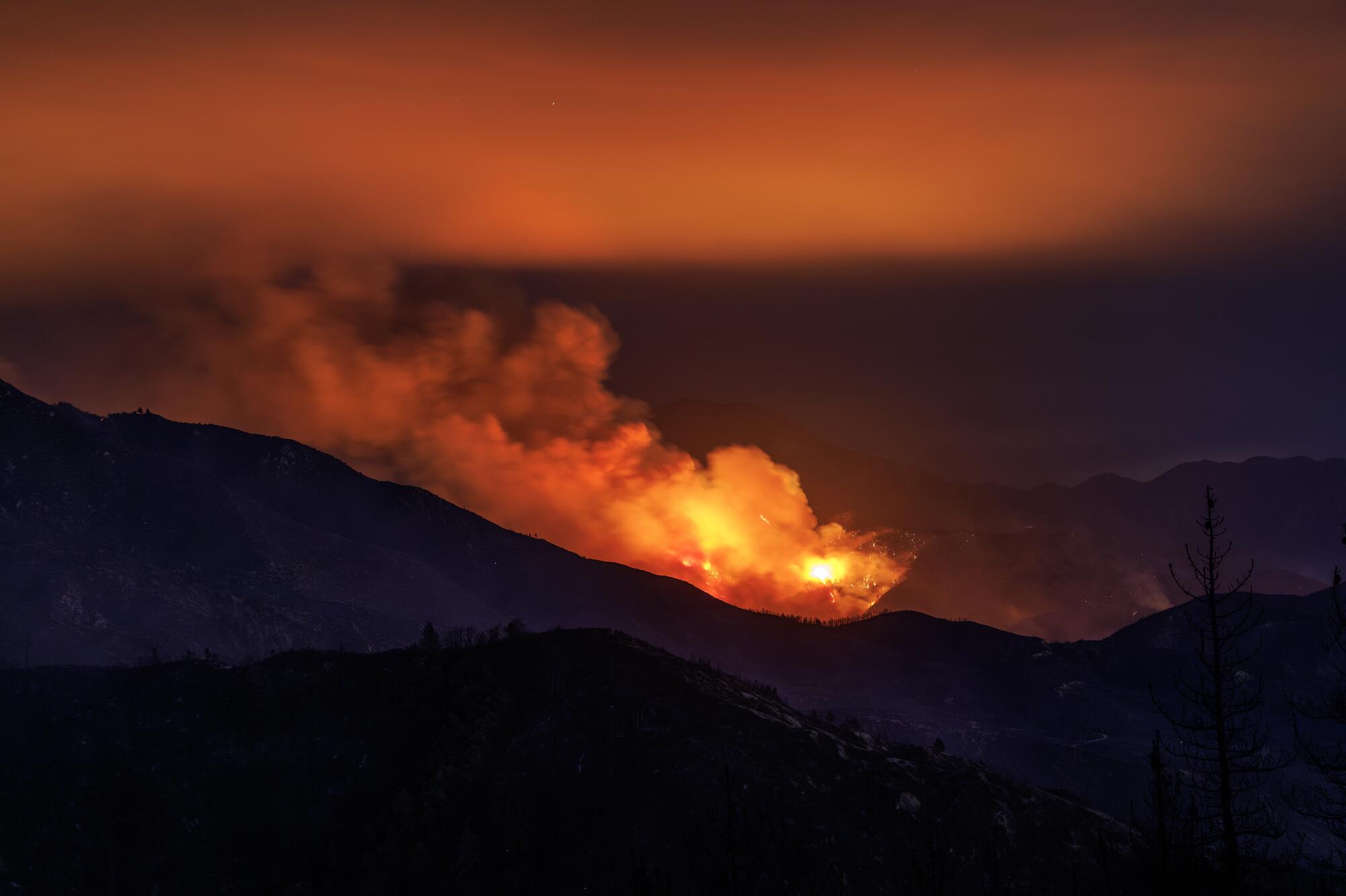 El humo y las llamas de la línea de fuego iluminan la cresta por la noche.