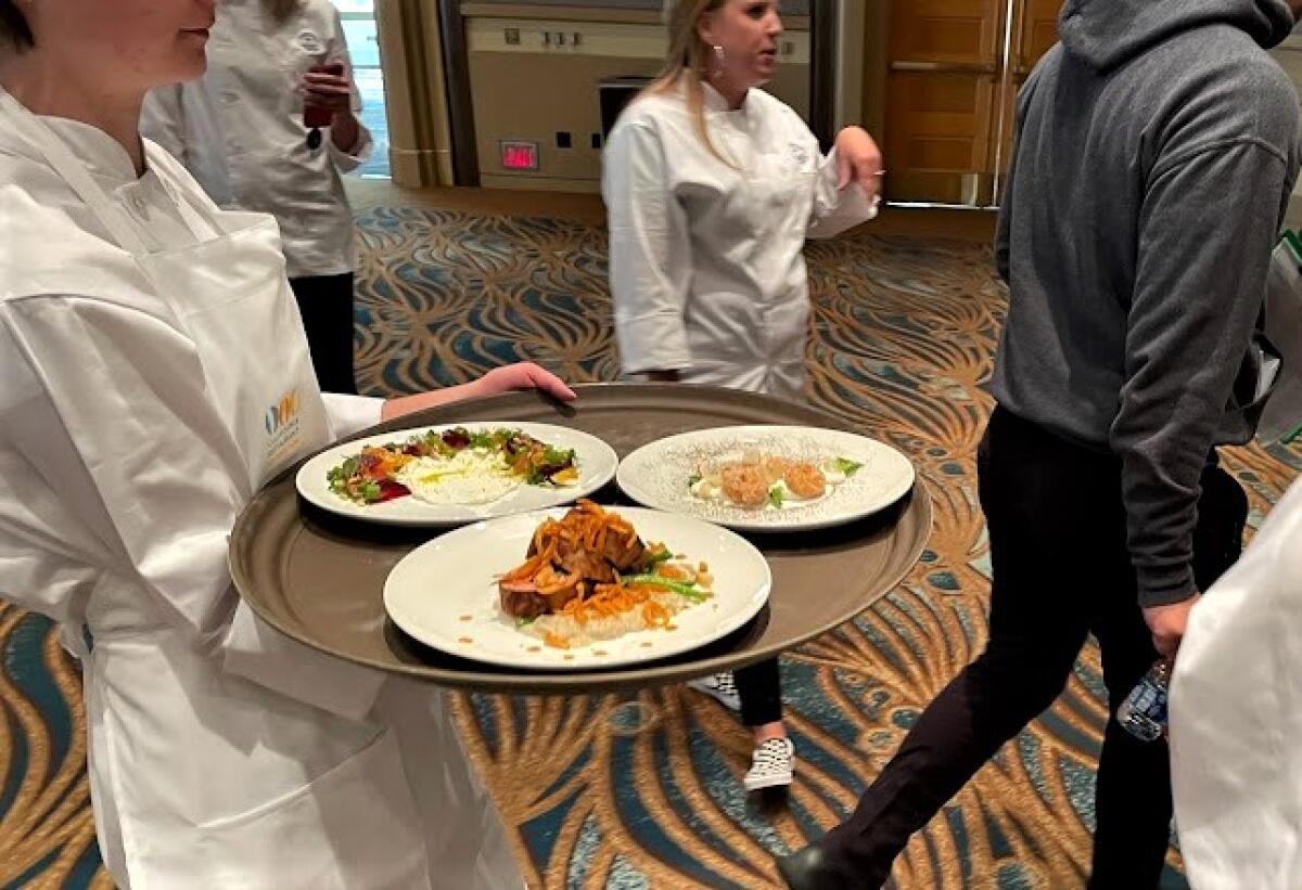 Members of the Newport Harbor High Culinary Team Monday walk their winning dishes to the judges table at the CA ProStart Cup.