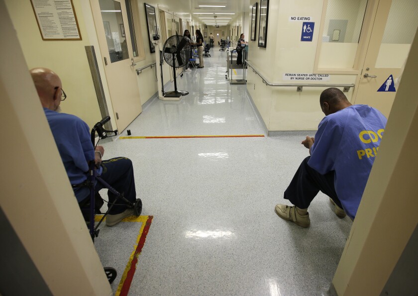 FILE — In this June 20, 2018, file photo, a pair of inmates wait for medical treatment at the California Medical Facility in Vacaville, Calif. Attorneys representing California inmates are urging state officials and a federal judge to advance one of every 10 prisoners to the front of the line for coronavirus vaccinations, saying it would help ease the burden on hospitals while helping control outbreaks inside state lockups. (AP Photo/Rich Pedroncelli, File)