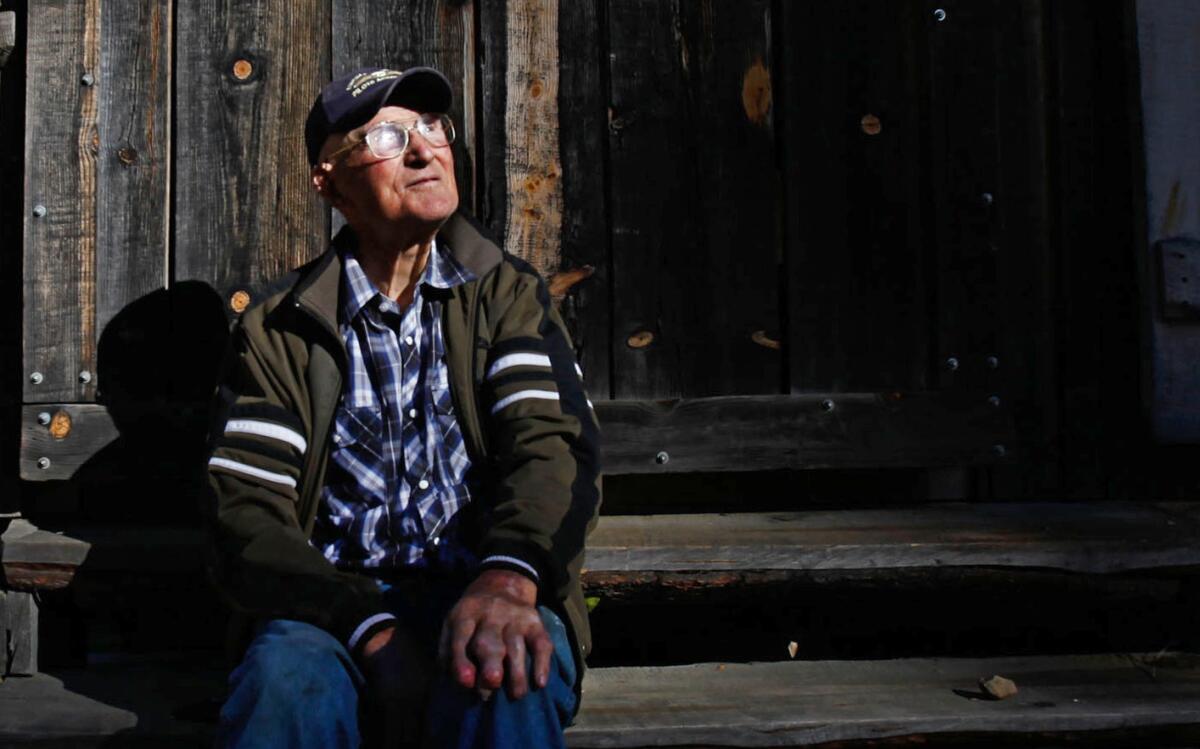 Sitting on the steps of his tool shed and work shop, Jack English, 94, tries to warm himself on a chilly morning in November 2013.