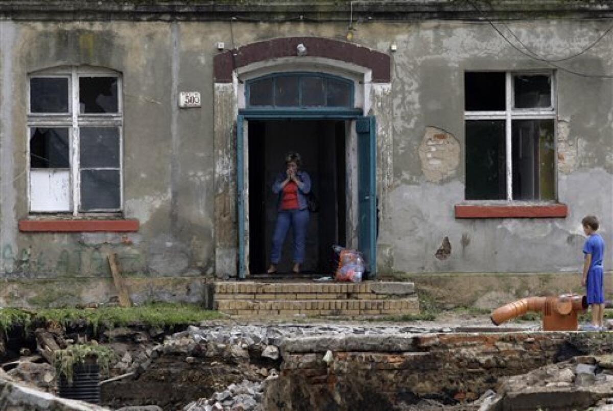 A resident reacts after her house was damaged in a flash floods that hit the town of Bogatynia, Poland, Sunday, Aug. 8, 2010. The flooding has struck an area near the borders of Poland, Germany and the Czech Republic. (AP Photo/Petr David Josek)