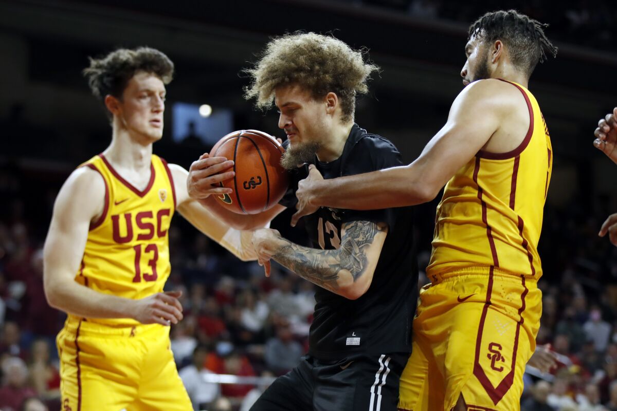 Long Beach State forward Romelle Mansel, center, pulls down a rebound between Southern California guard Drew Peterson, left, and forward Isaiah Mobley during the second half of an NCAA college basketball game in Los Angeles, Sunday, Dec. 12, 2021. (AP Photo/Alex Gallardo)