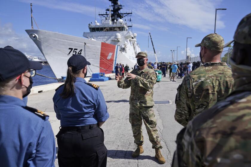 With the U.S. Coast Guard Cutter James behind him, Lt. Gen. Andrew Croft, center, Military Deputy Commander, U.S. Southern Command, speaks with Canadian and American Coast Guardsmen, Thursday, Aug. 5, 2021, at Port Everglades in Fort Lauderdale, Fla. The Coast Guard offloaded drugs worth more than $1.4 billion. The agency announced Thursday that the crew of the Cutter James offloaded about 59,700 pounds of cocaine and approximately 1,430 pounds of marijuana. (AP Photo/Wilfredo Lee)