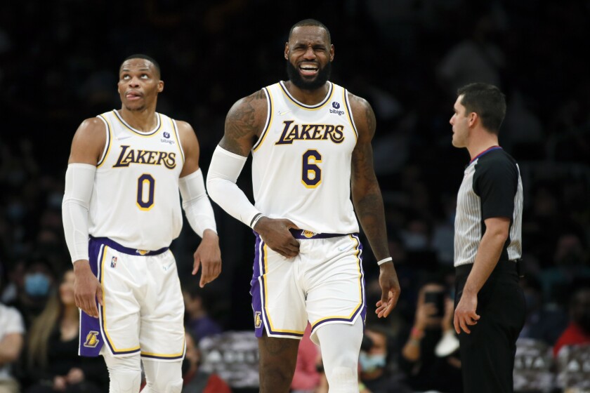 Los Angeles Lakers forward LeBron James, right, grimaces after making a basket against the Detroit Pistons, with guard Russell Westbrook, left, looking up at a video replay during the second half of an NBA basketball game Sunday, Nov. 28, 2021, in Los Angeles. (AP Photo/Alex Gallardo)