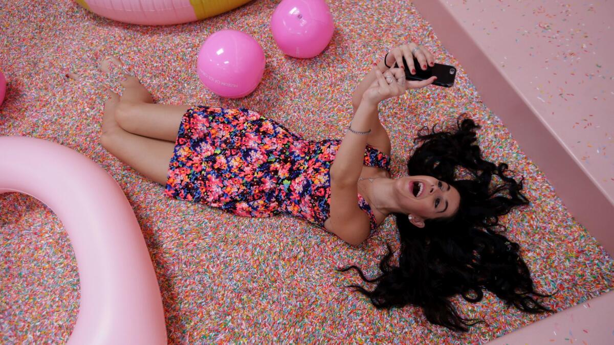 Deidre Behar takes a selfie in a pool of sprinkles at the Museum of Ice Cream, a pop-up art installation in Los Angeles.