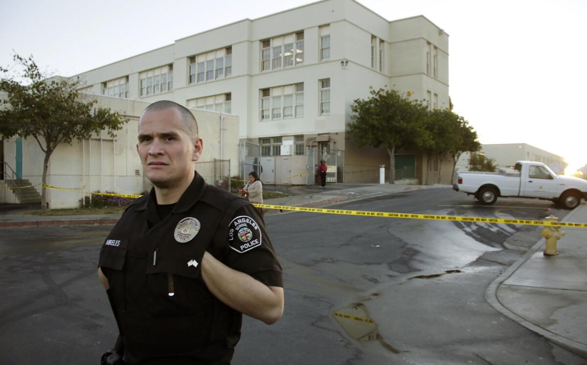 A school police officer stands guard near an area cordoned off after an early morning fire at Roosevelt High School in Boyle Heights.