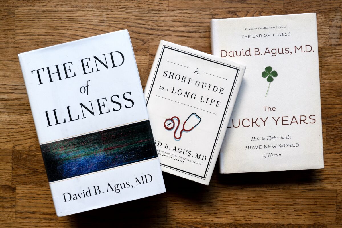 Three books by David Agus — "The End of Illness," "A Short Guide to a Long Life" and "The Lucky Years" — on a wood surface.
