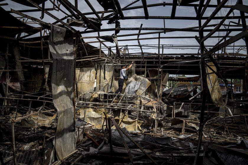 A man collects copper wires on the market which was destroyed after Russian bombardment in Nikopol, Ukraine, on Monday, Aug, 22, 2022. In Nikopol, across the river from Ukraine's main nuclear power plant, Russian shelling wounded four people Monday, an official said. The city on the Dnipro River has faced relentless pounding since July 12 that has damaged some 850 buildings and sent about half its population of 100,000 fleeing. (AP Photo/Evgeniy Maloletka)