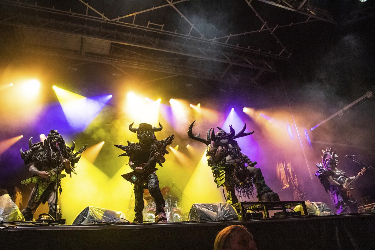 Gwar performs onstage with purple and yellow lights flashing in the background