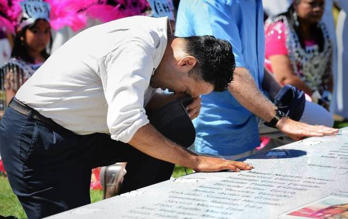 Musician Lance Canales bows his head at a memorial at Holy Cross Cemetery. The stone is inscribed with the names of the 28 farmworkers who died in a 1948 plane crash.