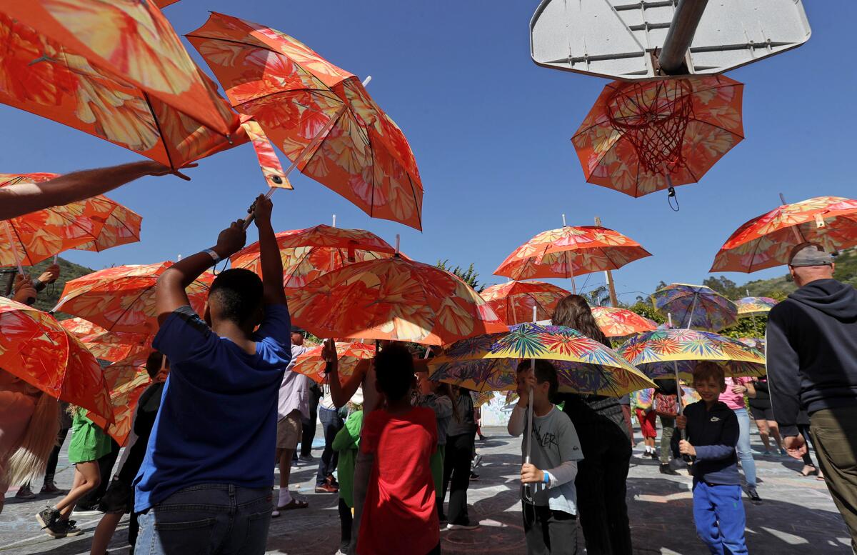 Kids spin and dance to drums as they open colorful umbrellas during the "Look Up" flash art experience.