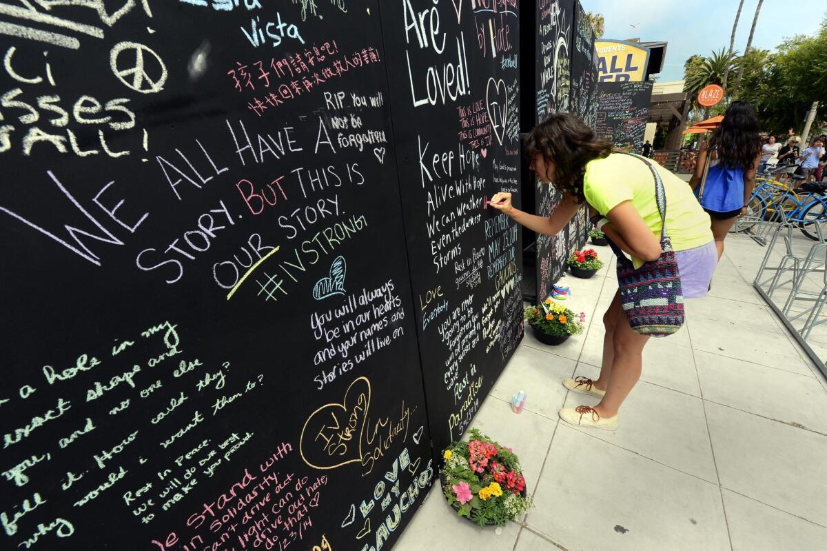 UC Santa Barbara student Samantha Lepore writes on the Wall of Remembrance near the site where seven people were killed and 13 wounded in a shooting rampage in the college town of Isla Vista, Calif.