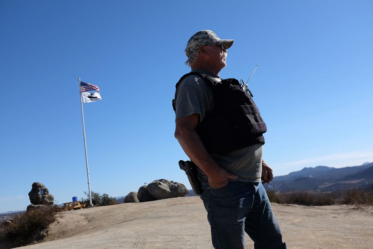 Robert Crooks watches the border fence for migrants crossing with a loaded semiautomatic pistol from a high perch dubbed Patriot Point.
