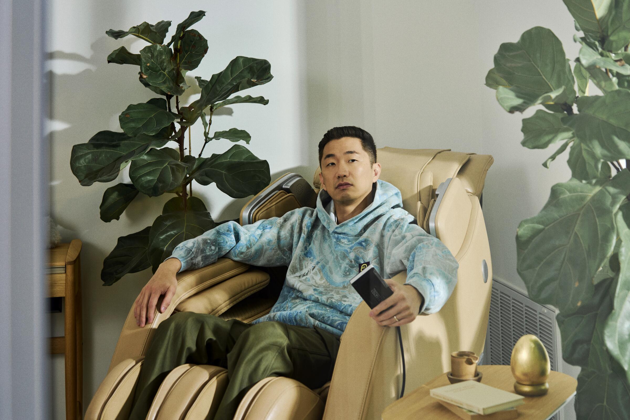Lee Sung Jin sits in a large massage chair.