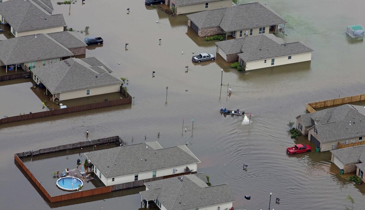 A boat motors between flooded homes after heavy rains inundate the region in Hammond, La.