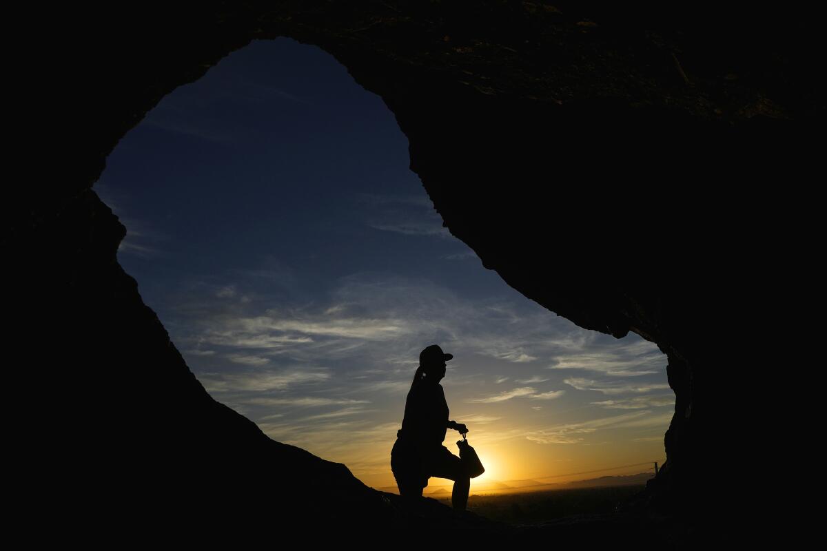 ARCHIVO - Un senderista pasa frente a la caverna Hole-in-the-Rock de Papago Park 