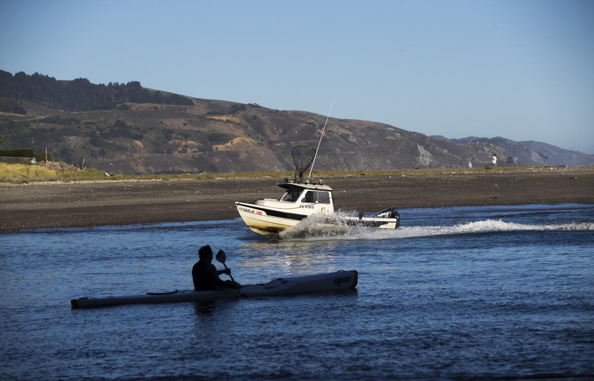 A kayaker paddles out as a fisherman returns in Bolinas Bay.