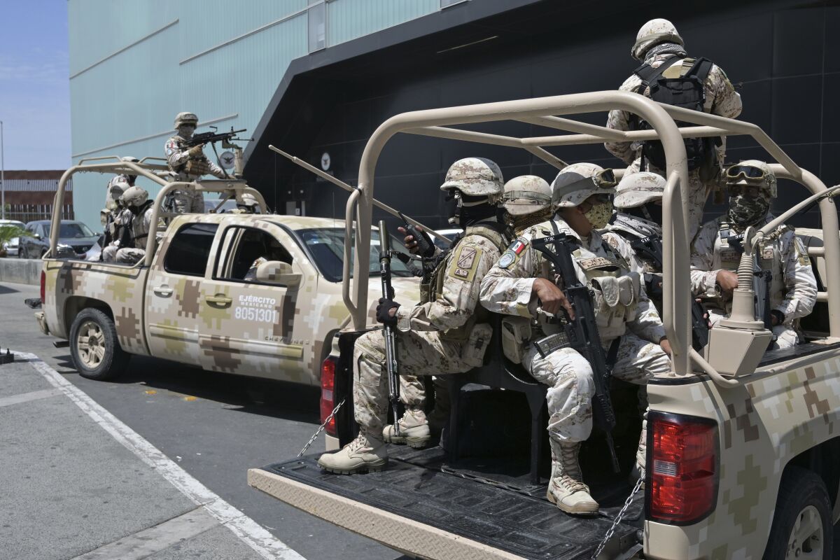 Armed military members in trucks.