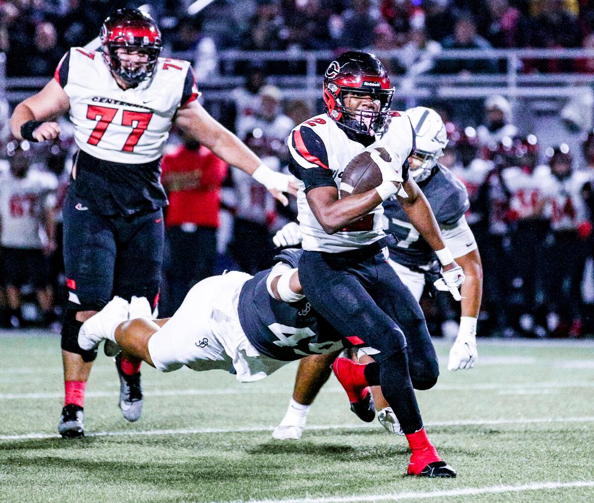 Corona Centennial High's Cornell Hatcher Jr. tries to evade a couple of defenders as he breaks through the line of scrimmage.