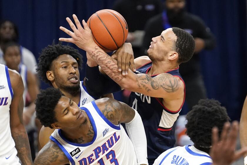 Connecticut's Tyrese Martin, right, battles DePaul's Pauly Paulicap and Darious Hall (13) for the ball during the first half of an NCAA college basketball game Monday, Jan. 11, 2021, in Chicago. (AP Photo/Charles Rex Arbogast)