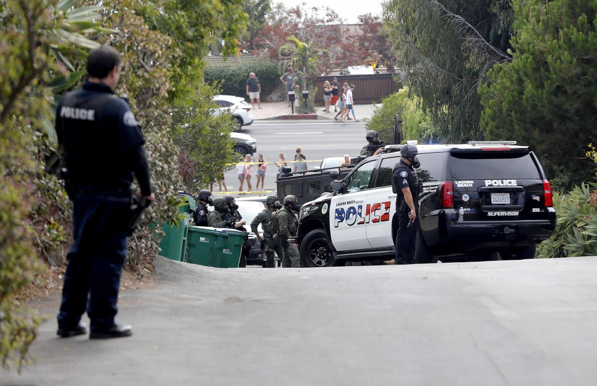Laguna Beach police watch over the scene as a SWAT team prepares to extract a barricaded suspect from a home.
